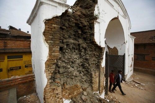 Personas pasean a través de la puerta dañada el día después del terremoto en Bhaktapur