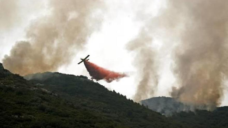 Una avioneta lanzando agua ayer para tratar de frenar el avance de las llamas.