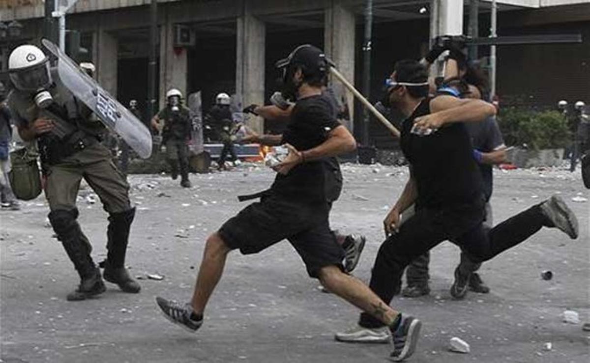 Joves manifestants agredeixen violentament un policia antiavalots.