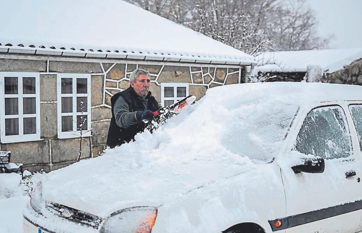 Un hombre retira la nieve de su coche en Ourense.