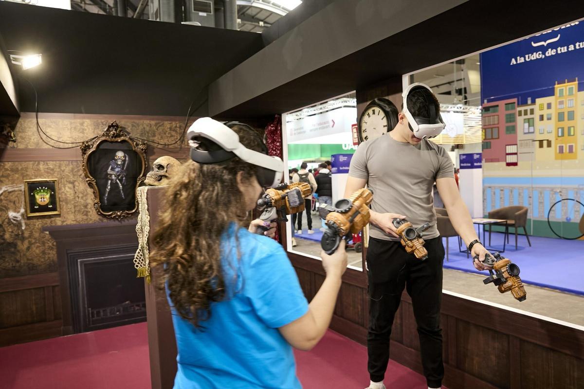 Dos jóvenes juegan con dispositivos de realidad virtual en el Saló de l'Ensenyament de 2024.
