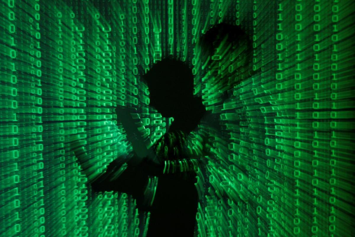 FILE PHOTO: An illustration picture shows a projection of binary code on a man holding a laptop computer, in an office in Warsaw June 24, 2013. REUTERS/Kacper Pempel/Illustration/File Photo