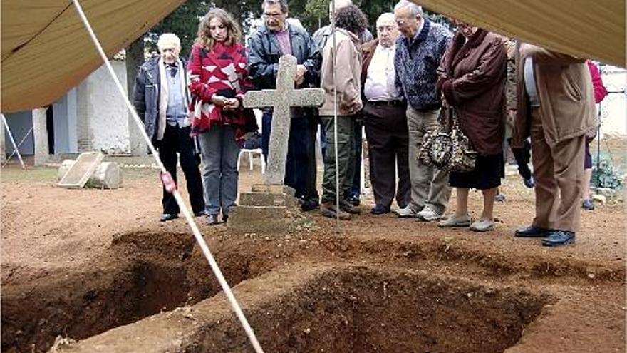 Hijos y familiares de los &quot;ocho de Benagéber&quot; observan los restos de la fosa común antes de su exhumación.