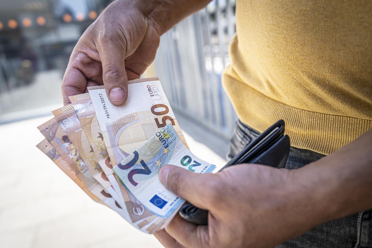 Un trabajador rumano empleado hasta ahora en las obras del Camp Nou muestra el dinero que le han pagado tras cesarlos.