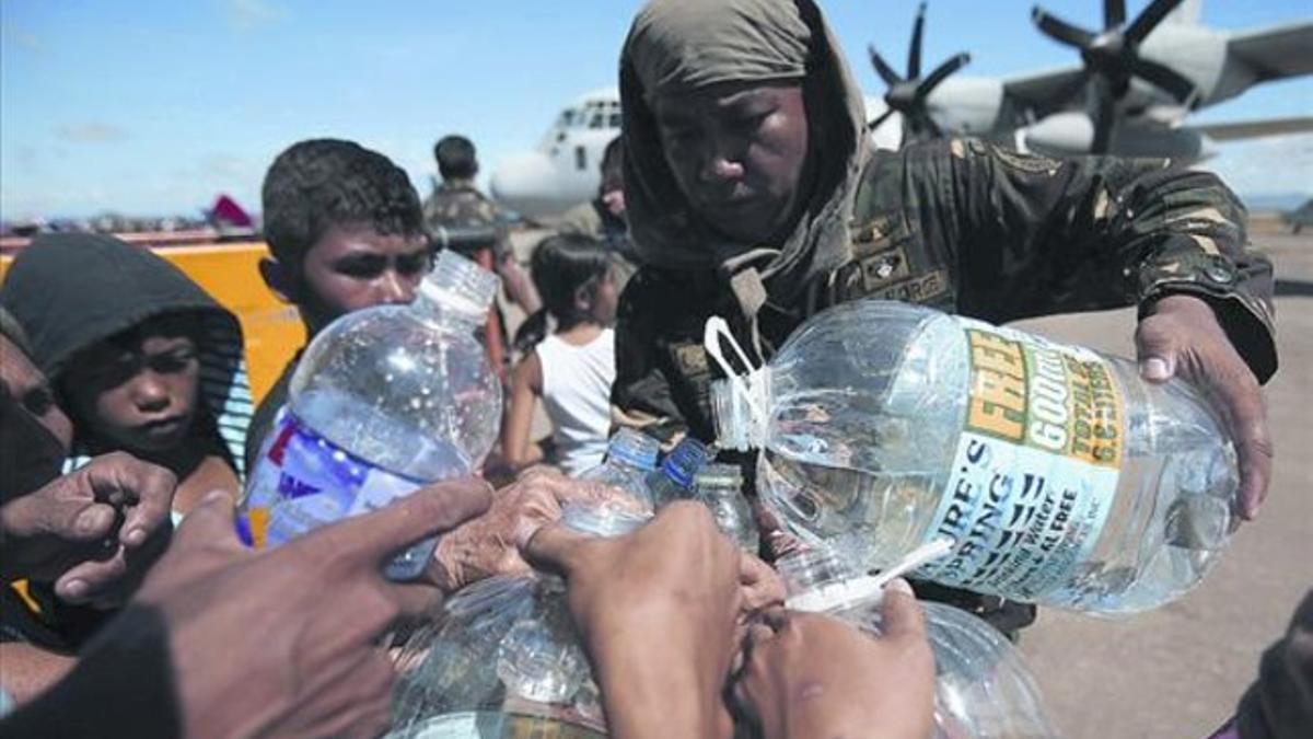 Un soldado filipino distribuye agua potable a afectados por el tifón en la localidad de Tacloban.