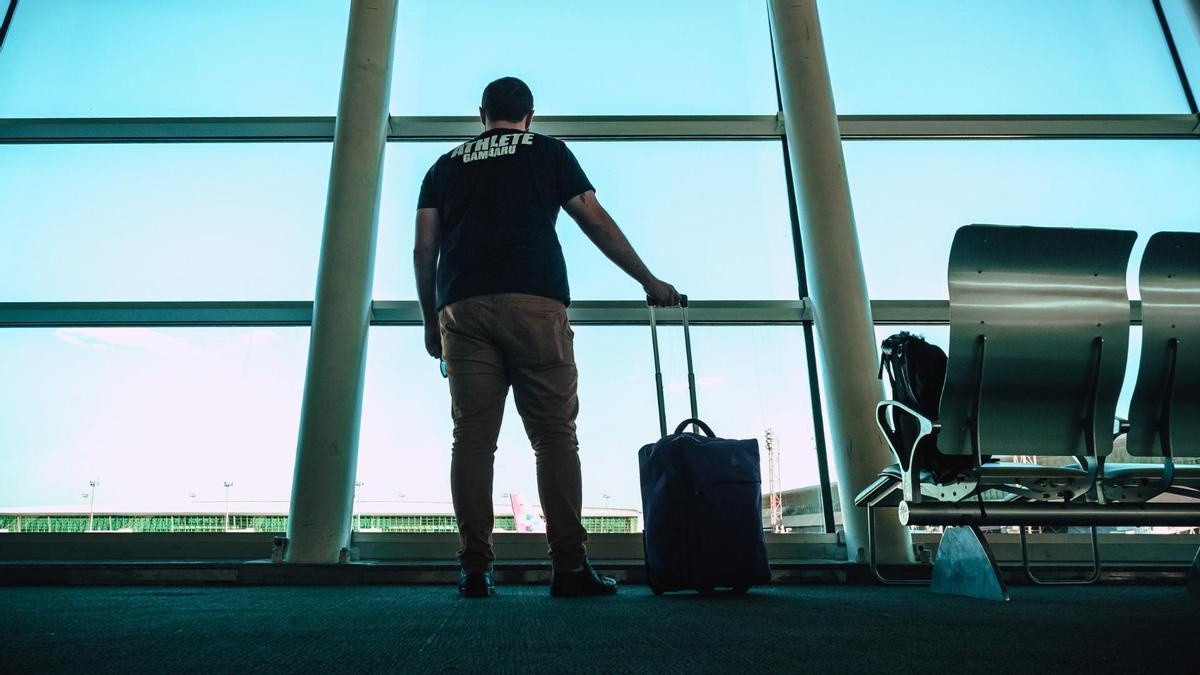 Un hombre en un aeropuerto con su equipaje de mano.