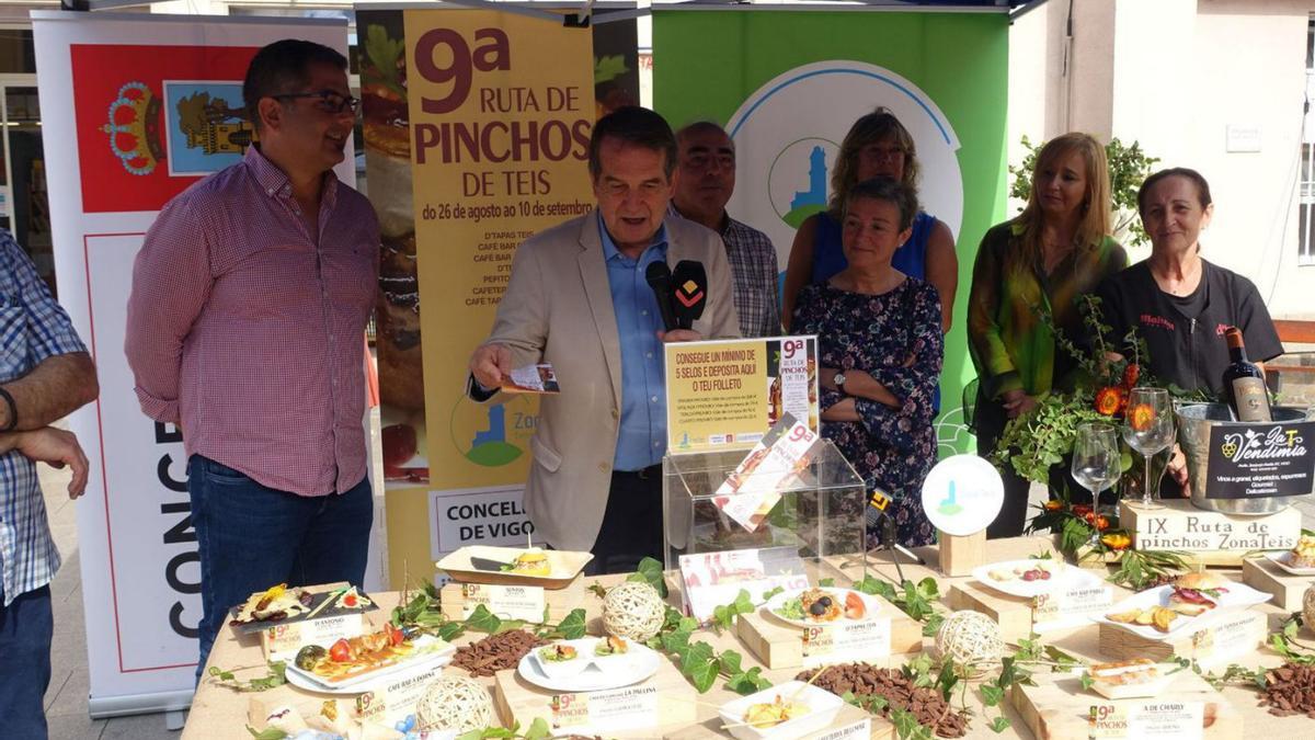 Presentada la 9ª Ruta de Pinchos de Teis.  La asociación de comerciantes de Teis presentó este miércoles el programa de su 9ª edición de la “Ruta de Pinchos” por el barrio que se celebrará del viernes 26 de agosto al sábado 10 de septiembre. En el acto, además del alcalde de la ciudad, Abel Caballero, estuvieron presentes María Jesús Román, presidenta de Zona Teis Centro Comercial; a presidenta do Mercado de Teis, Purificación Santos, e o presidente da Federación Vigo Comercio, Roberto Giráldez.  | FARO