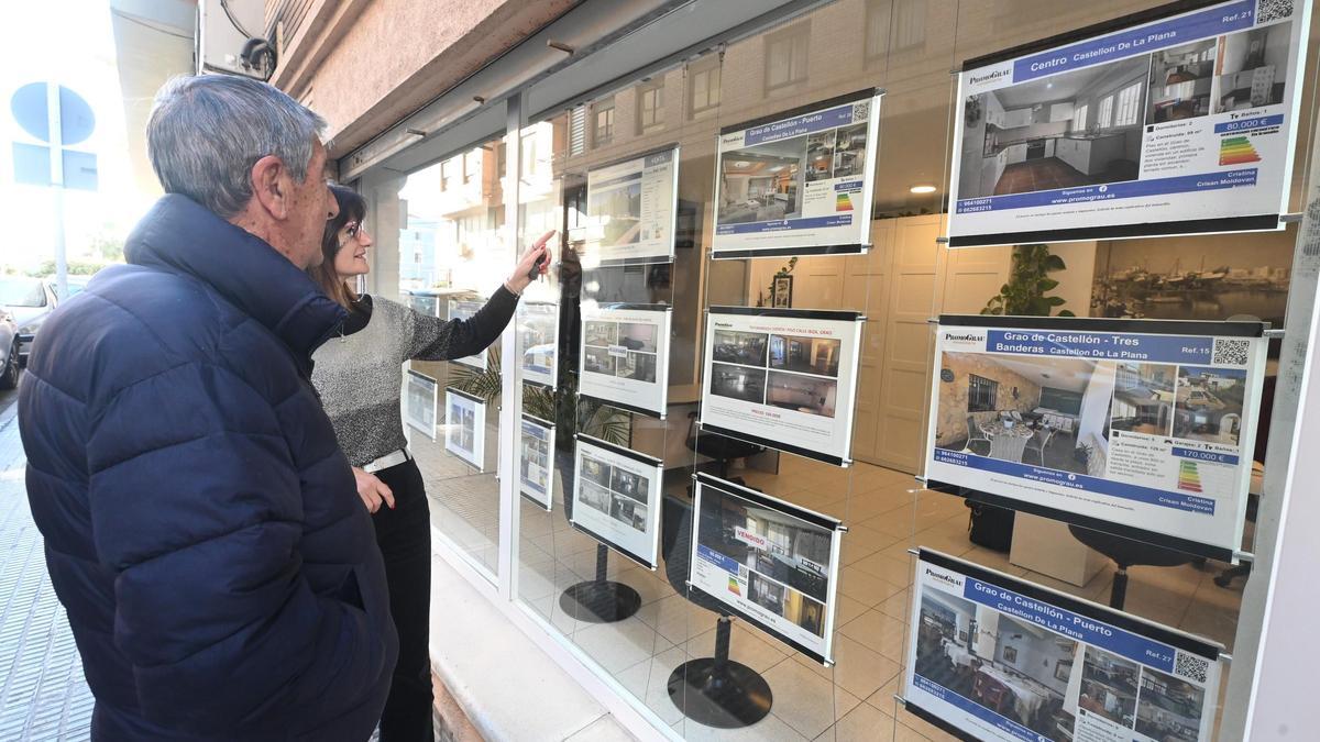 Dos personas miran los inmuebles disponibles a la venta en una inmobiliaria de Castellón.