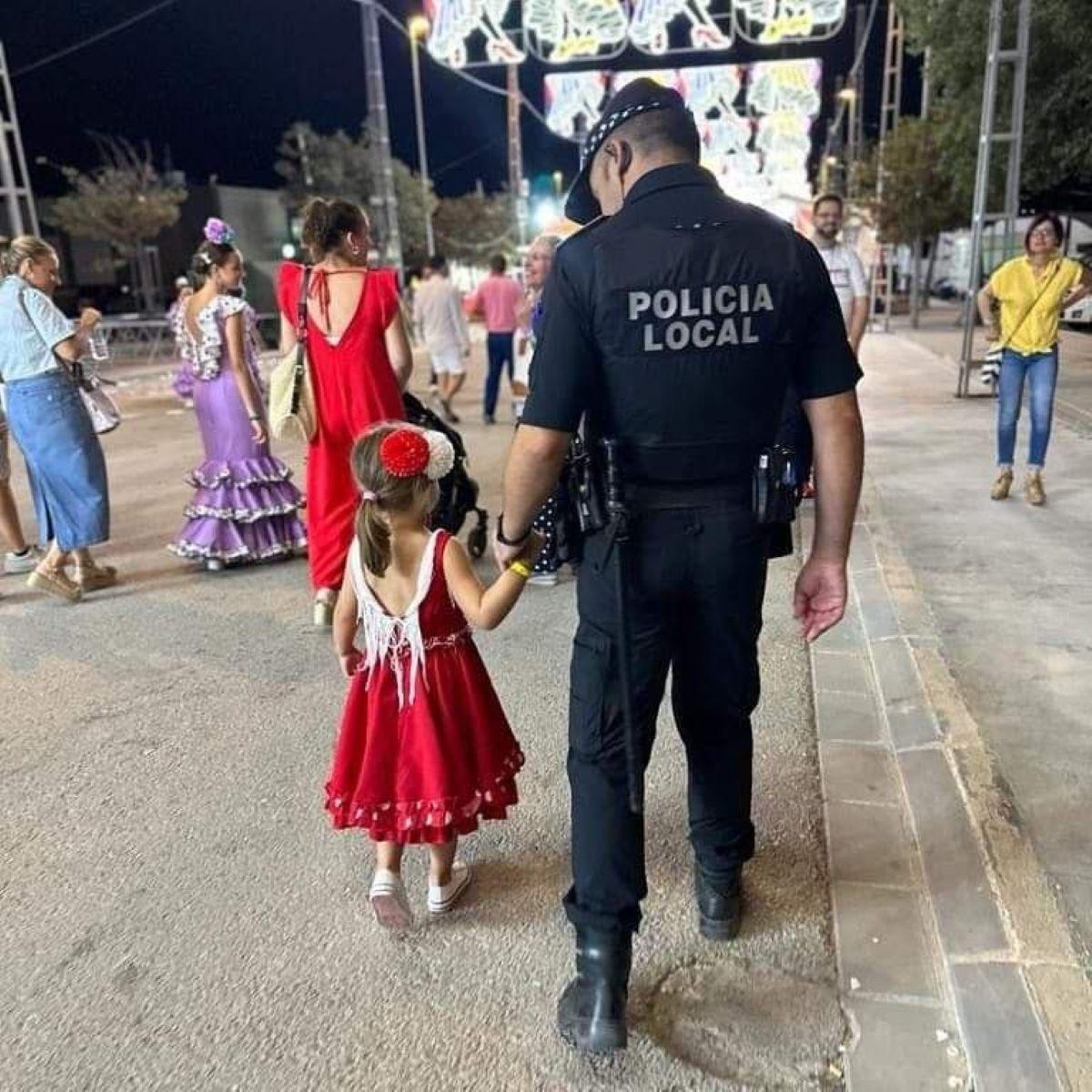 Un policía local acompaña a una niña en el recinto ferial, en una edición anterior.