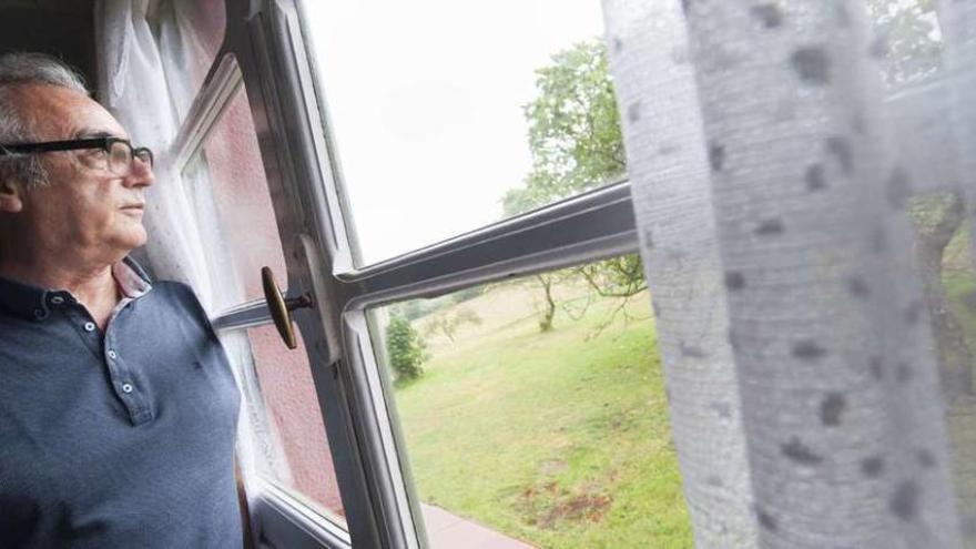 El escritor Juan José Millás, mirando por la ventana de la cocina de su casa en Asturias. /