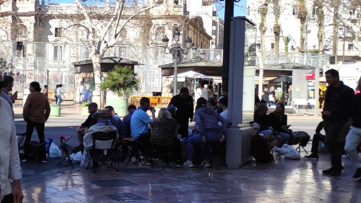 Gent asseguda en cadires a la plaça de l'Ajuntament de València per a veure la mascletà.