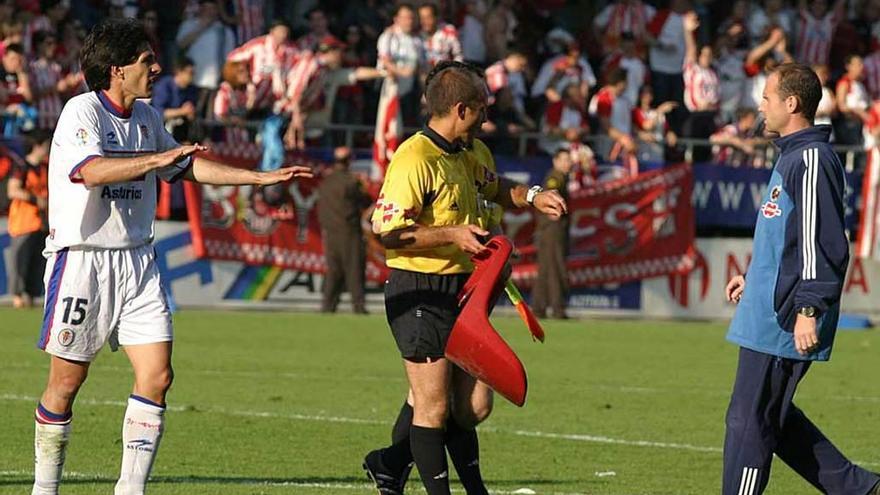 Rodado Rodríguez retira una butaca lanzada al campo ante el jugador del Sporting Ismael Irurzun.