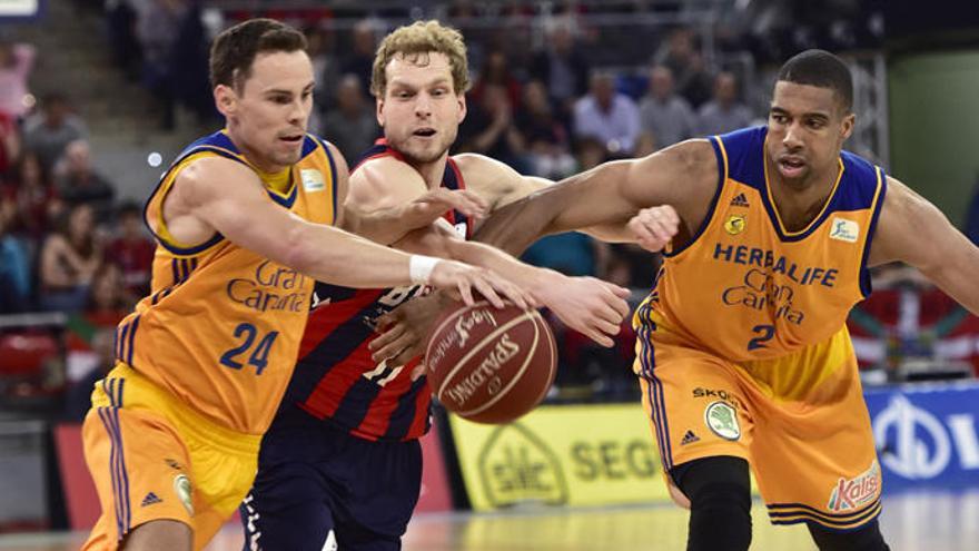 Los jugadores del Herbalife Gran Canaria, Kyle Kuric (i) y Richard Hendrix (d), luchan con el esloveno del Baskonia Jaka Blazic (c)