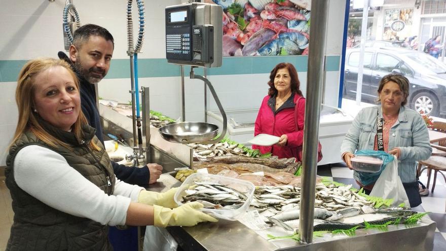 Manuel Boullosa y Sonia García despachan el pescado a dos clientas en táperes.  // ALBA VILLAR