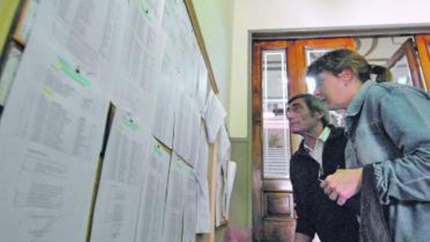 Dos personas consultan las listas provisionales en el Ayuntamiento.