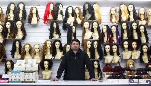 Kashir Mir poses for a photograph at his workplace, Juliet Wig Shop, in the London constituency of Brent Central
