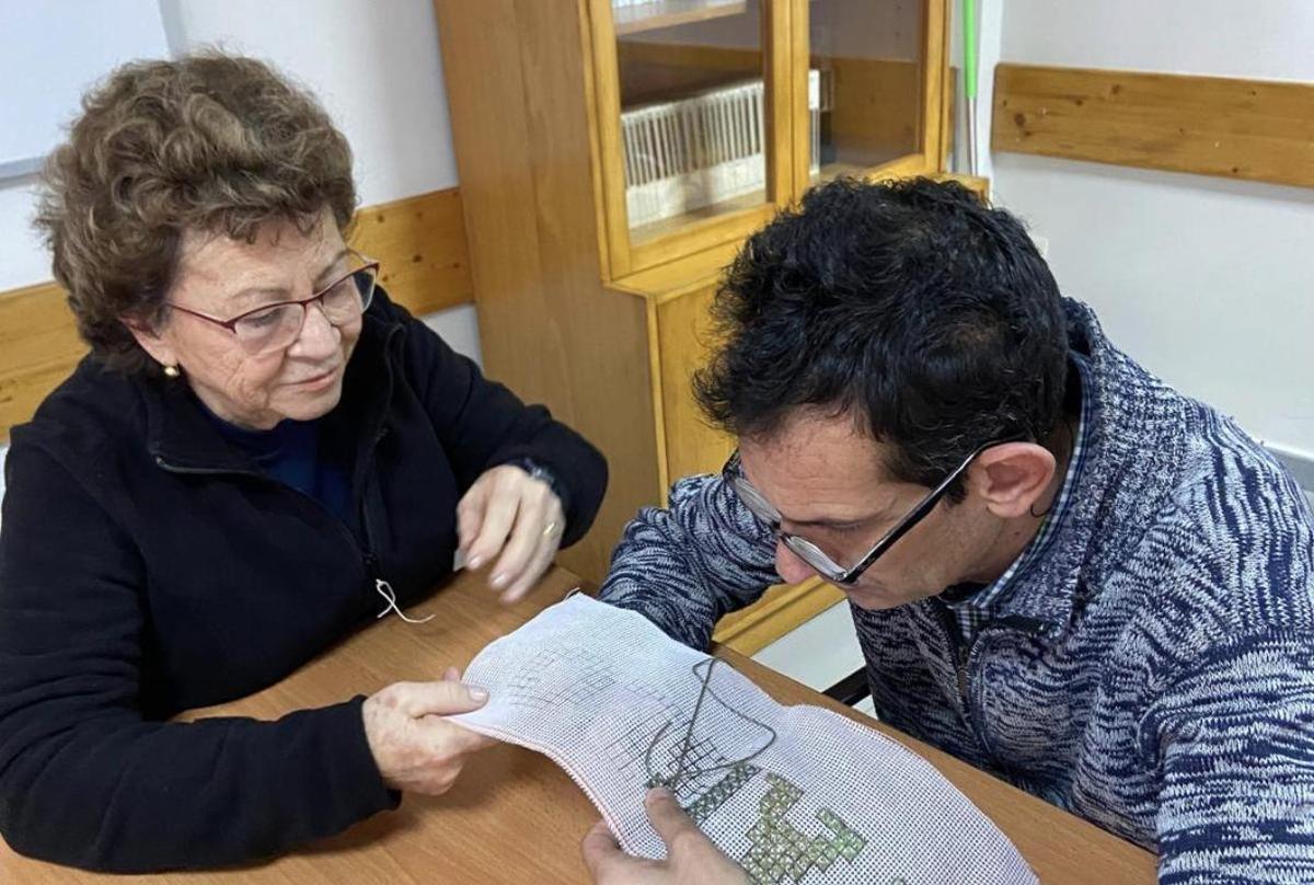 Una voluntaria enseña punto de cruz a uno de los participantes en los talleres