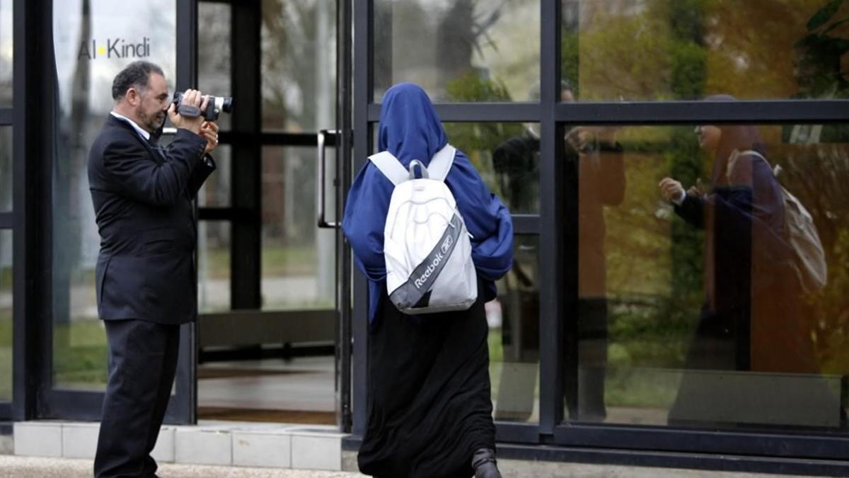 Un miembro de la escuela musulmana de secundaria Al Kindi filma a una estudiante mientras entra en el centro educativo en Decines, cerca de Lyon (Francia).