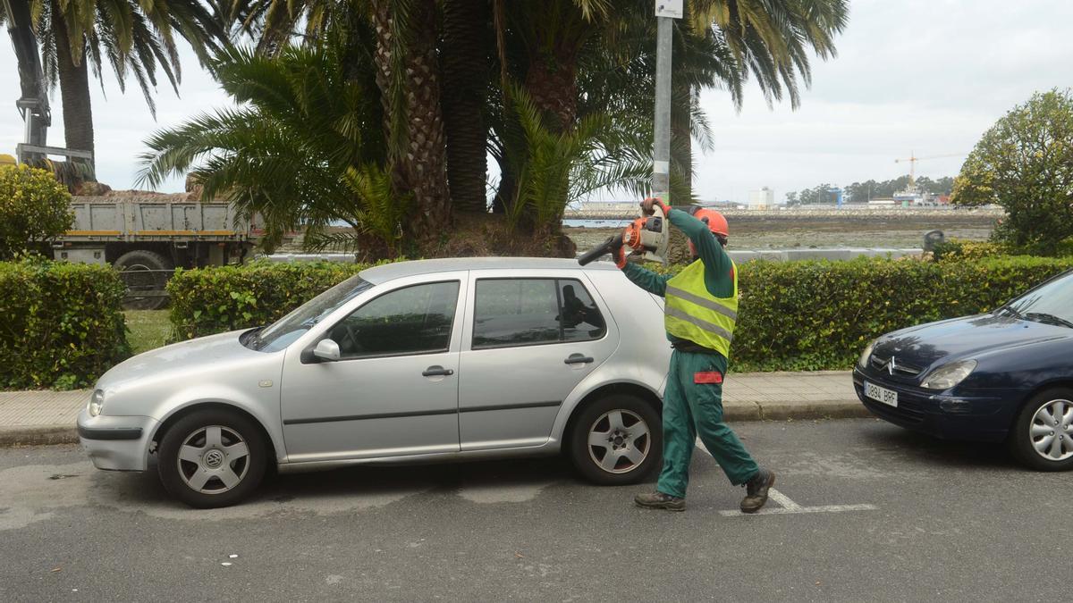 Un operario limpia el polvo de los coches estacionados en las inmediaciones del paseo marítimo