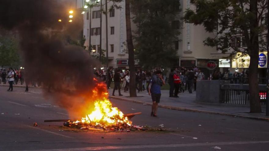 Manifestantes prenden fuego a una barricada en Santiago.