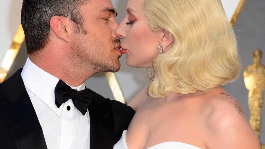 El beso y una emocionante canción. Lady Gaga besa al actor Taylor Kinney; la cantante conmovió al público con su actuación.