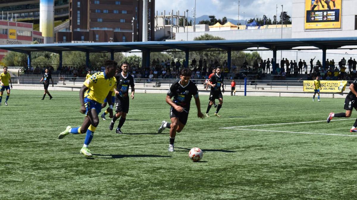 Saliou, de Las Palmas Atlético, se interna por la banda perseguido por un defensa, ayer en el Anexo.