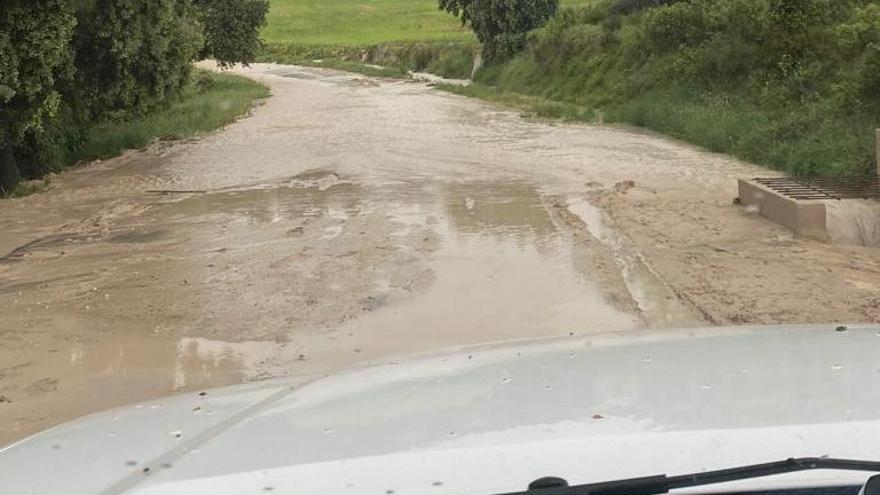 Una vecina circula en su vehículo por la zona tras haber llovido.