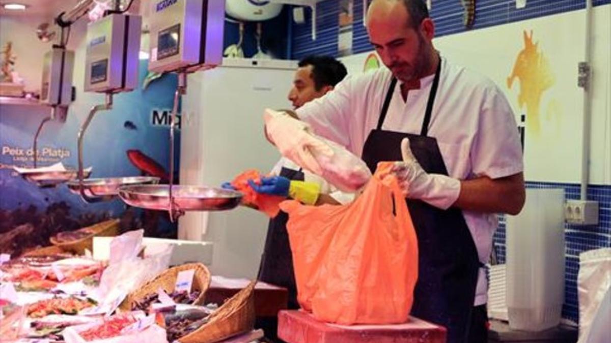 Ya de pago 8Un pescadero pone una compra en una bolsa de plástico, ayer en el mercado de Sant Antoni.