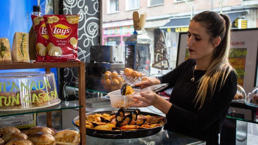 La camarera del Café Loft sirve en un recipiente una ración de paella.