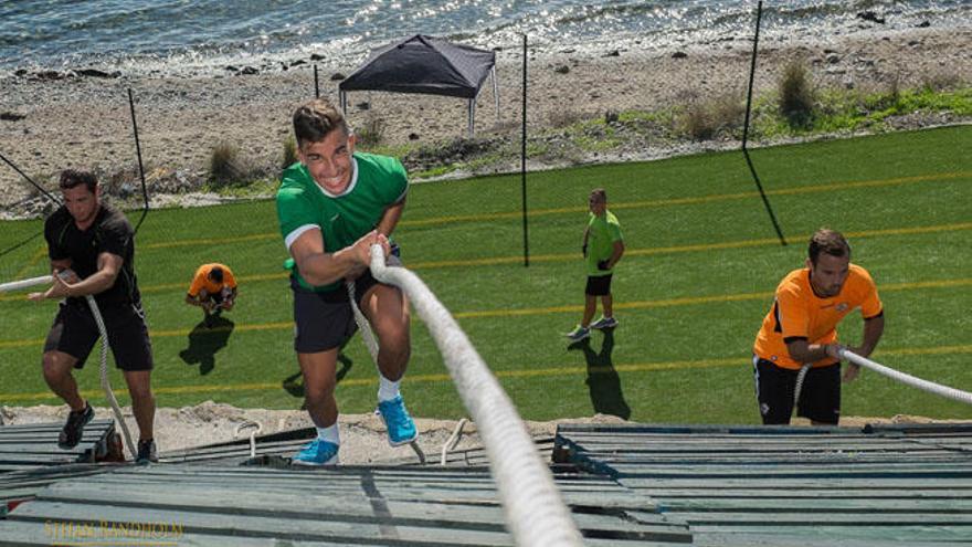 Varios deportistas trepan por cuerdas desde la pista inclinada que conduce a la playa.