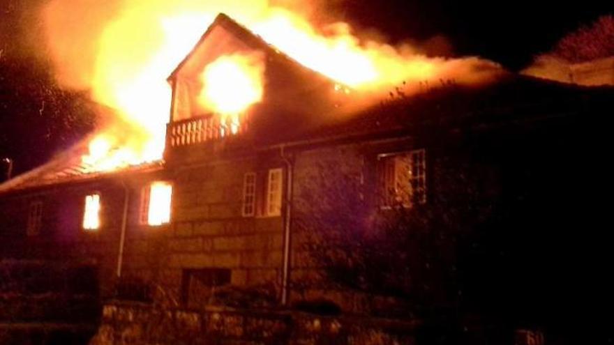 Arriba, vista de la fachada entre las llamas. Debajo, uno de los efectivos contraincendios que acudieron a sofocar el fuego de noche en Moscoso.  // Álvaro M. Leiro