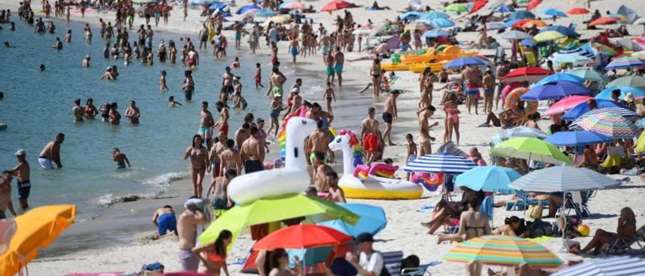 Gente disfrutando ayer del día de playa en el arenal sanxenxino de Areas que presentaba un lleno casi absoluto. |   // GUSTAVO SANTOS