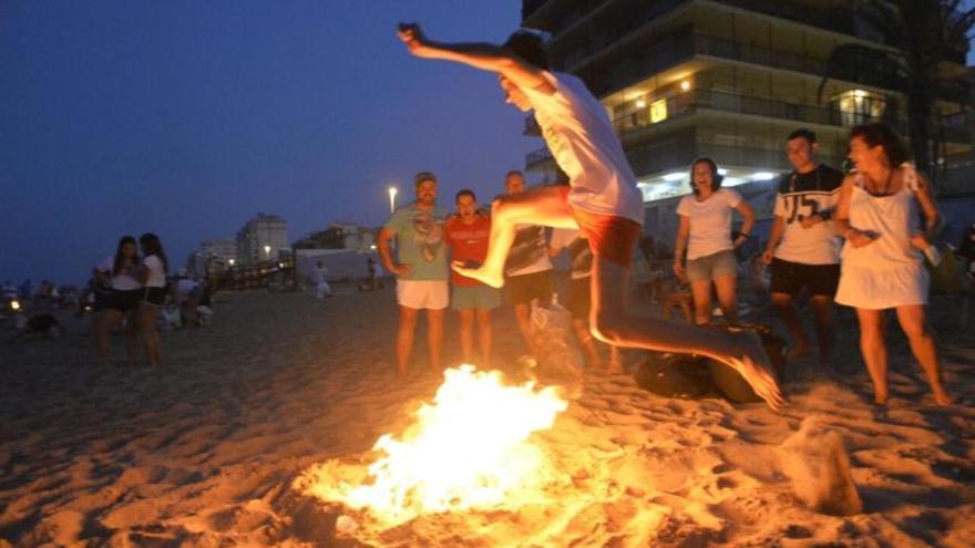 Un joven salta una hoguera en la playa de Los Arenales.