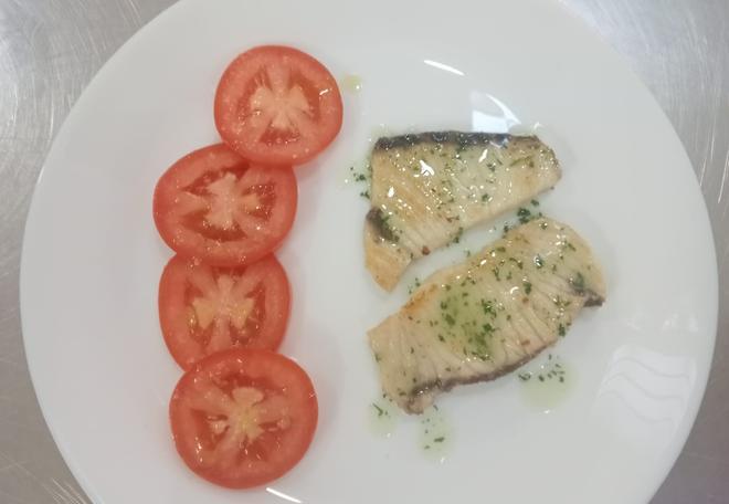 Proceso de elaboración de un plato de caella a la plancha con tomates frescos.