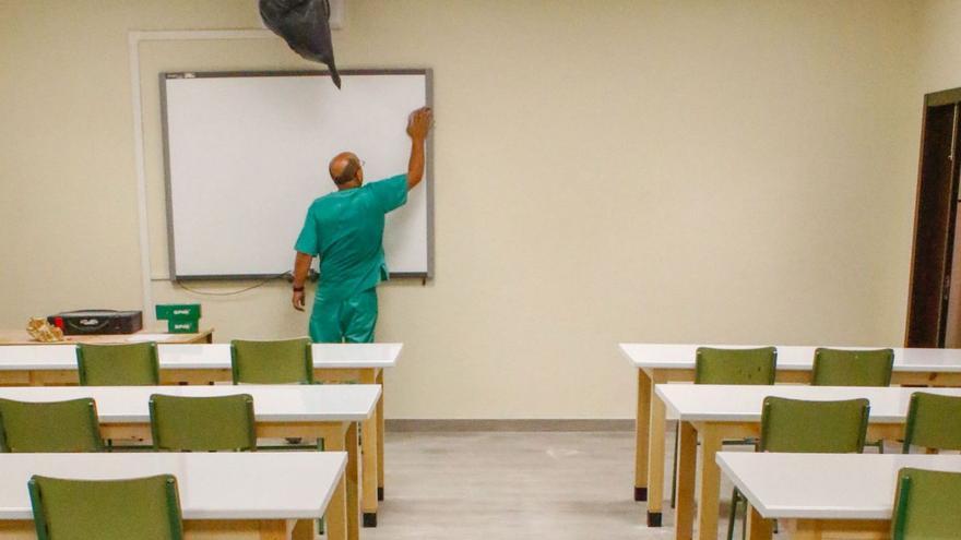 Un operario limpia un aula de un centro educativo.