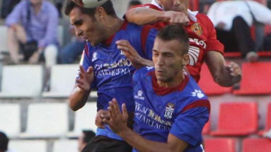 Dos futbolistas del Cartagena pugnan con uno del Nástic durante el encuentro de ayer. / la opinión