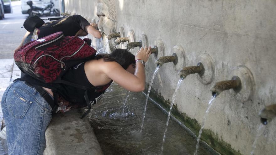 Dos personas se refrescan en la fuente de los 25 chorros en Xàtiva.