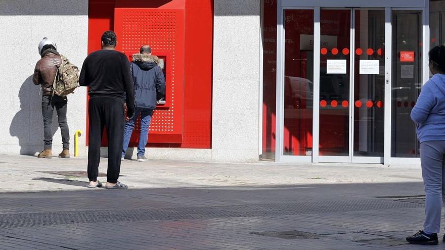 Personas hacen cola en la puerta de un cajero.