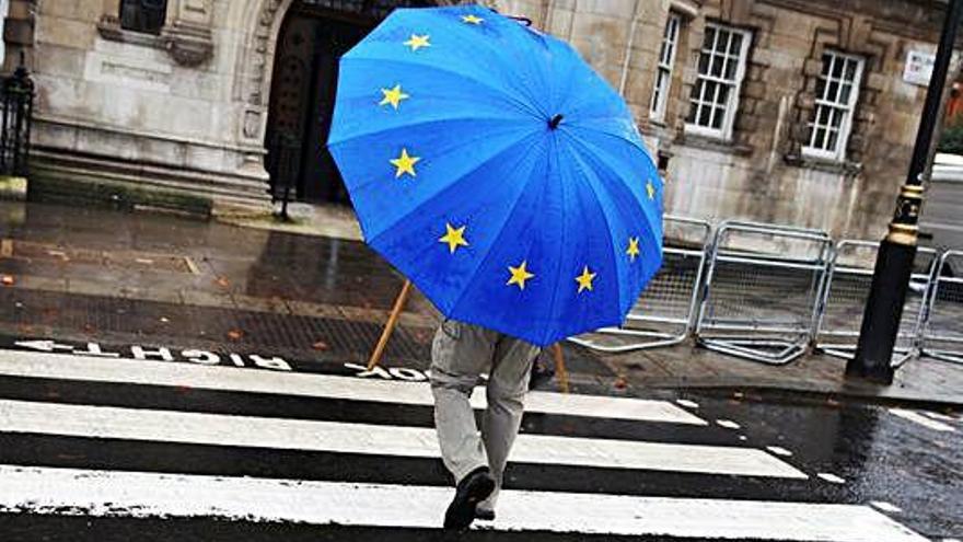 Un ciutadà es protegeix de la pluja, a Londres, amb un paraigua