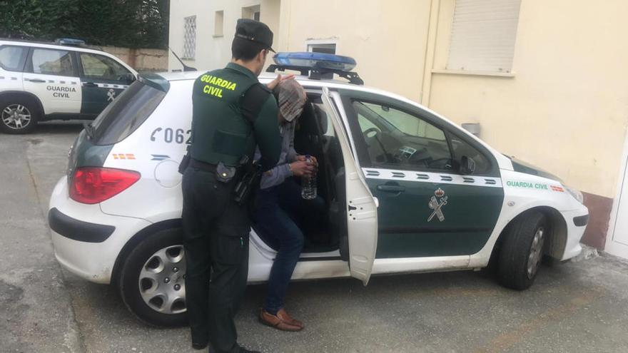 un agente conduce al detenido por el asalto al establecimiento hostelero