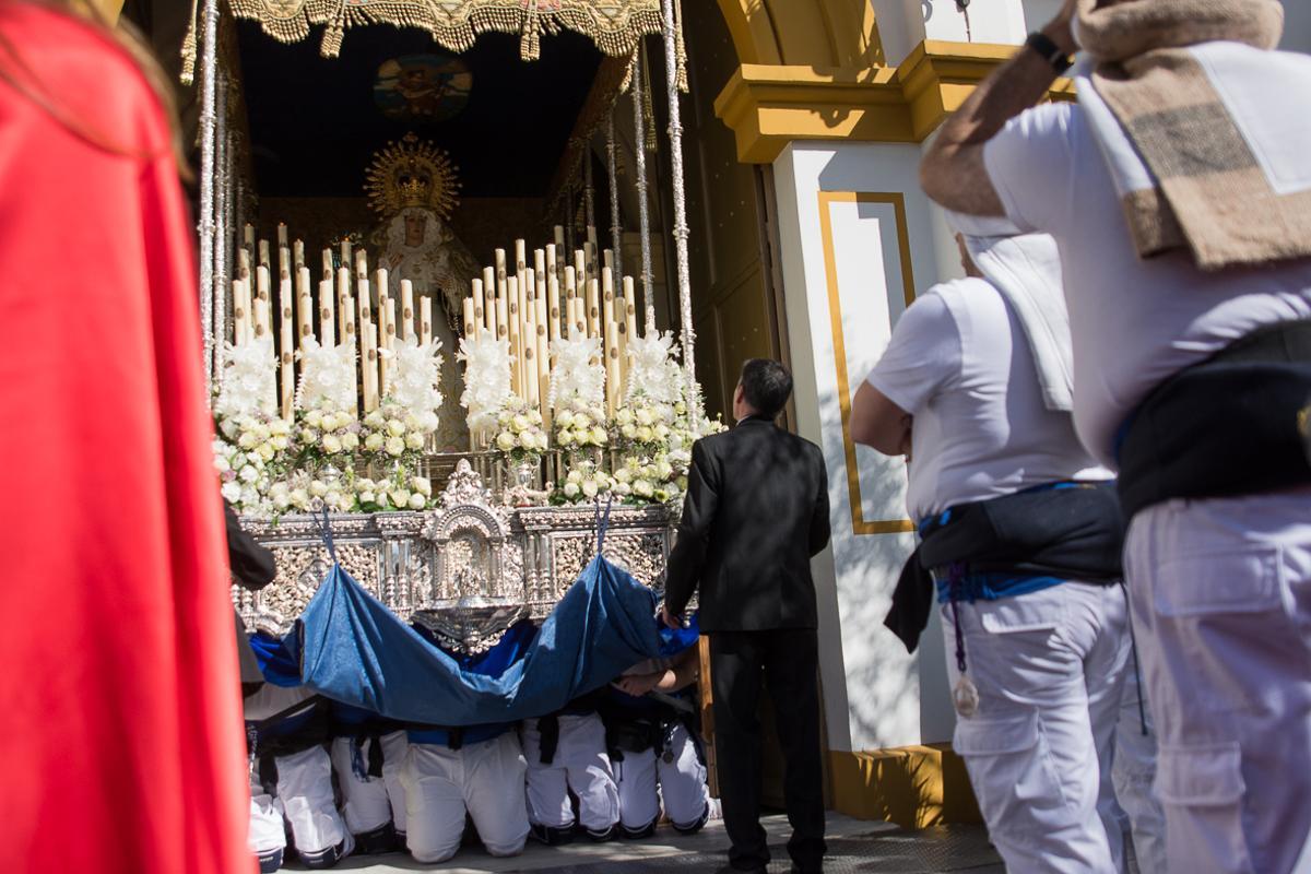 Los costaleros, de rodillas, sacan a la Virgen de la Palma.