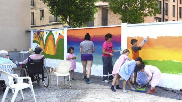 Niños decoran un muro en la residencia de mayores.