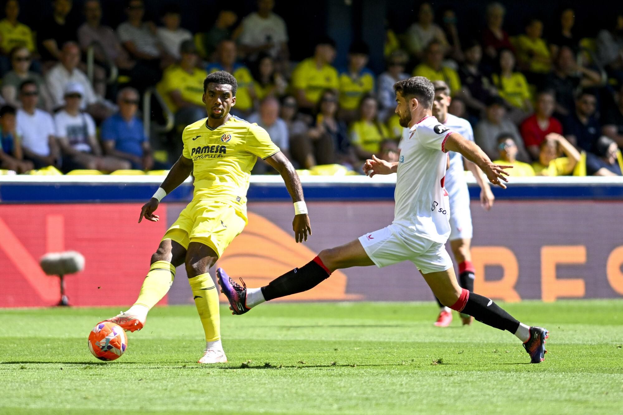 VILLARREAL (CASTELLÓN), 25/05/2025.- El defensa del Villarreal Logan Costa (i) pelea un balón ante el delantero del Sevilla Álvaro García este domingo, durante el partido de la jornada 38 de LaLiga EA Sports, que Villarreal y Sevilla disputan en el Estadio de la Cerámica. EFE/ Andreu Esteban