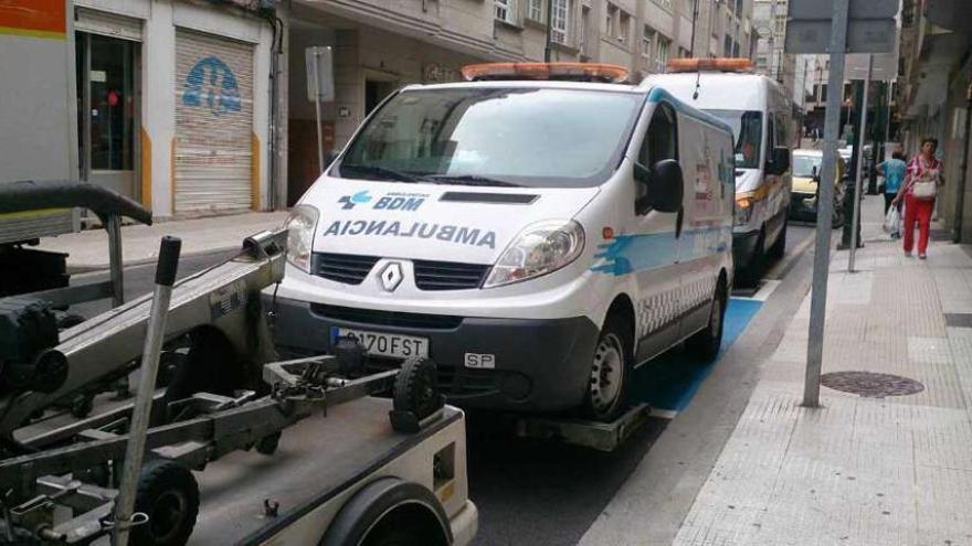 La grúa se lleva una de las ambulancias inmovilizadas por la Policía Local.