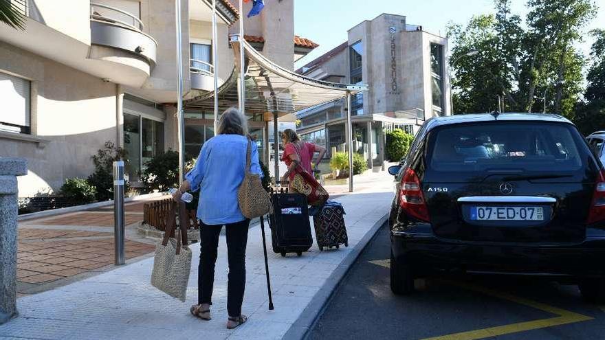 Una pareja de turistas a la entrada de un hotel en Sanxenxo. // Gustavo Santos