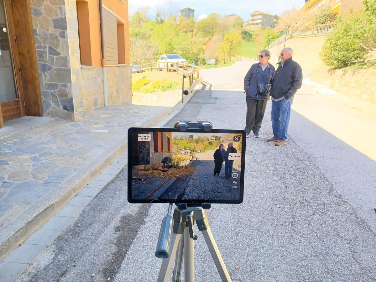 Veïns de Saldes provant la nova aplicació al costat d'un gall fer virtual, aquest dilluns