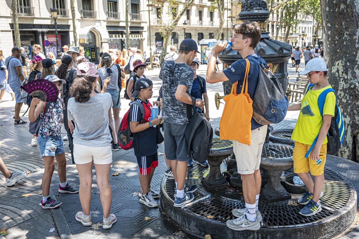 Ola de calor en Barcelona. turistas se refrescan en la fuente de canaletas así como también sus mascotas.