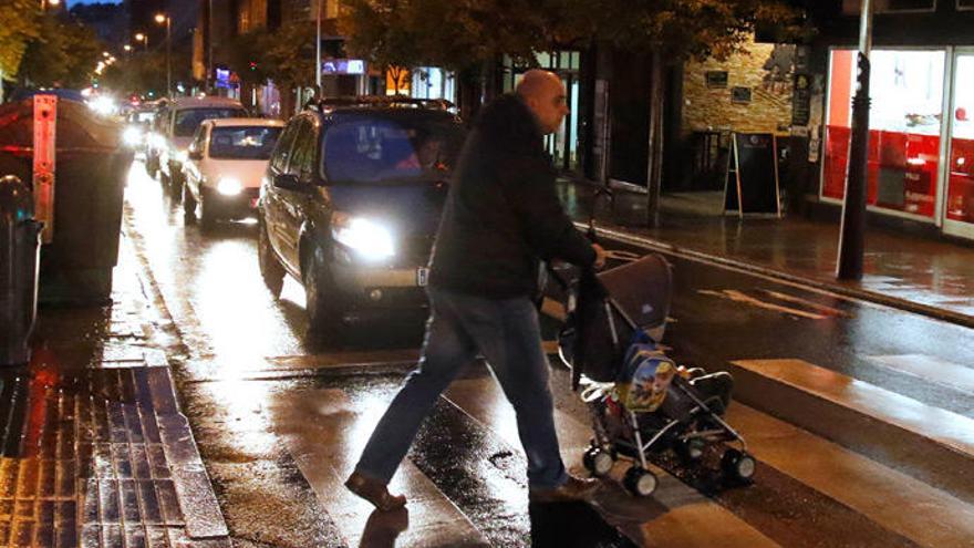 Un hombre cruza un paso de peatones con un carrito de bebé.