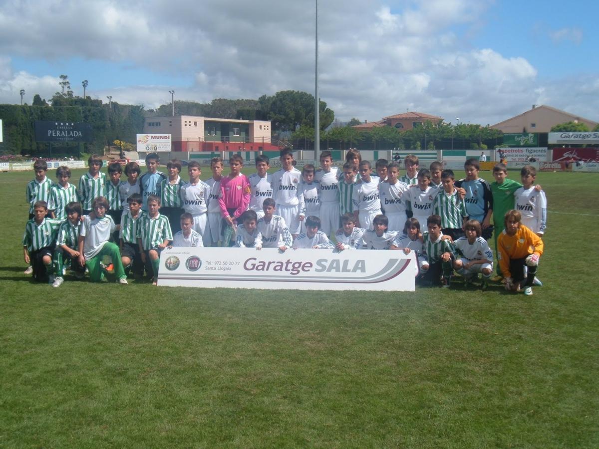 Álvarez, a sobre la lletra L del cartell publicitari, en la foto de família entre Madrid i el Betis a Peralada.