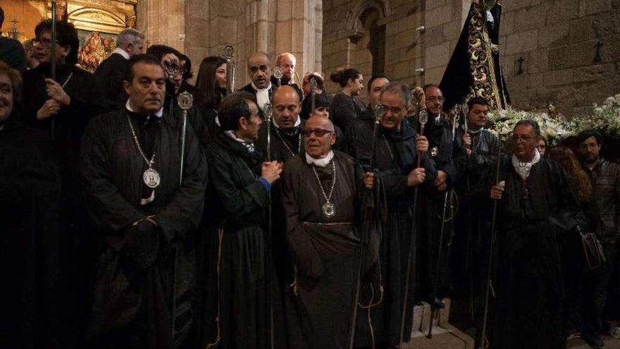 Hermanos con el medallón que contiene el anagrama de la cofradía y la Virgen de la Soledad.